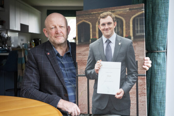 Man holding photo of son and looking at camera