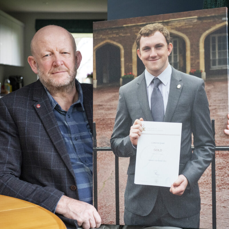 Man holding photo of son and looking at camera