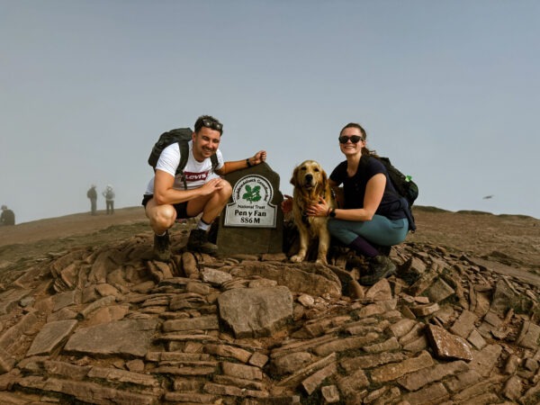 Man and a woman on top of a mountain with a dog