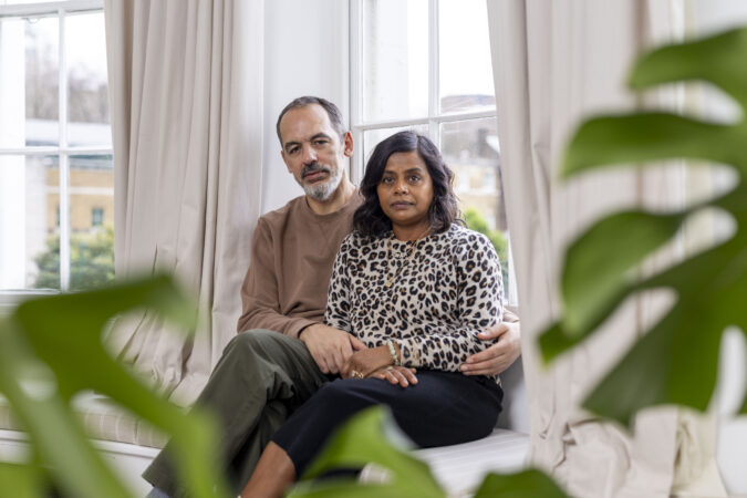 Couple sat by window looking at camera