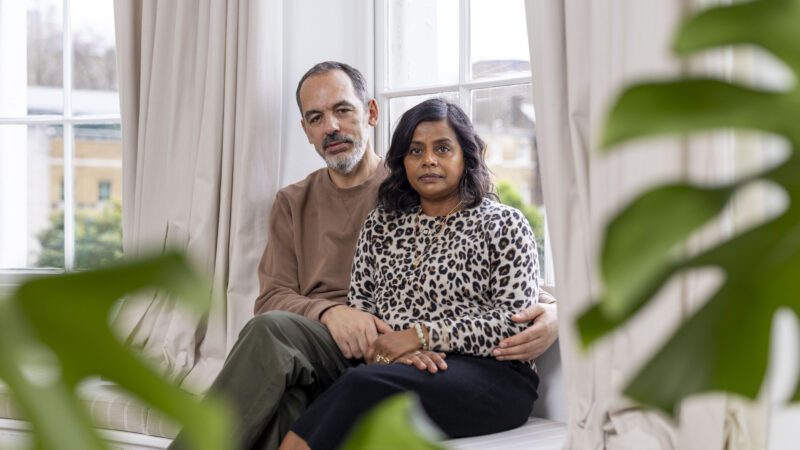 Couple sat by window looking at camera