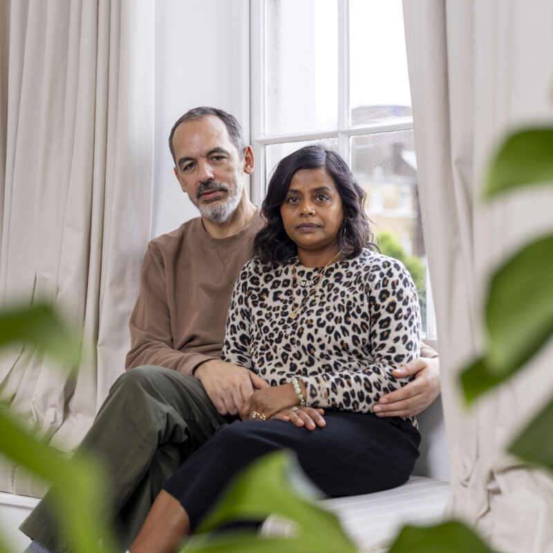 Couple sat by window looking at camera